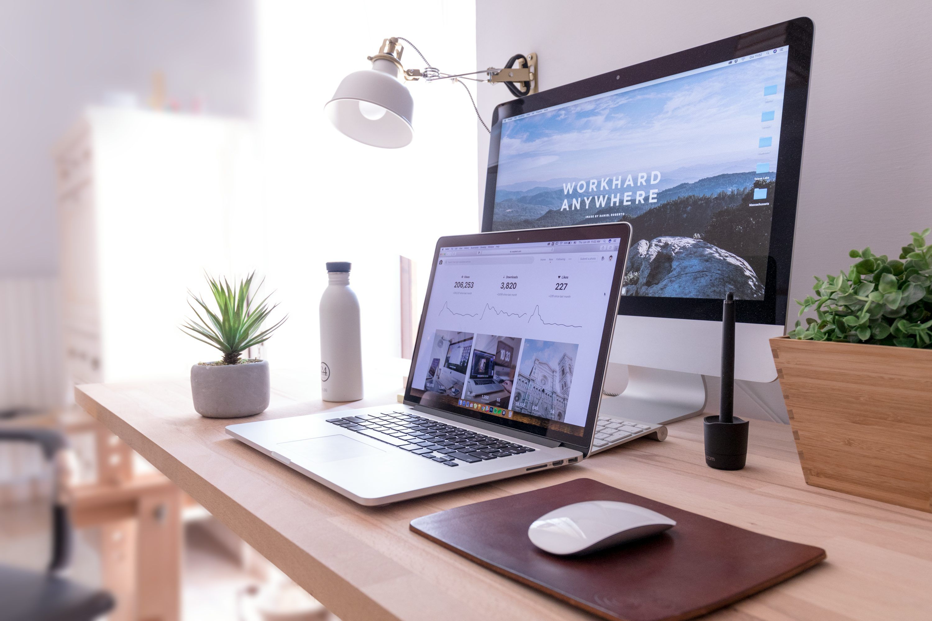Laptop webes felülettel és statisztikákkal egy monitor melletti munkaasztalon